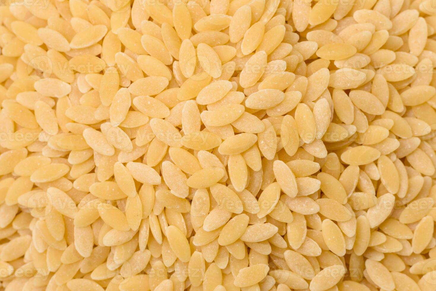Raw whole grain orzo pasta as an ingredient for a delicious dish photo