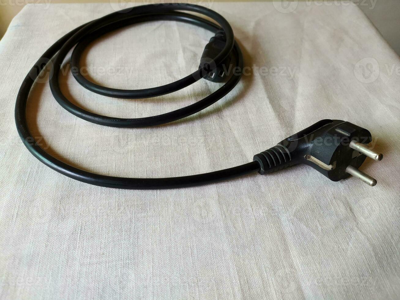 The black power cable was rolled up in a mess on the table photo