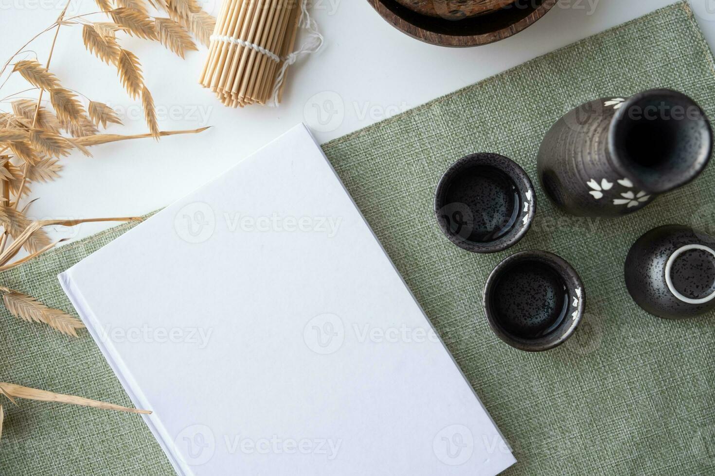 Book mockup design. Blank white book on dining table in asian style with tableware photo