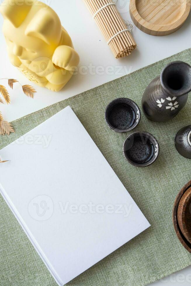 Book mockup design. Blank white book on dining table in asian style with tableware photo
