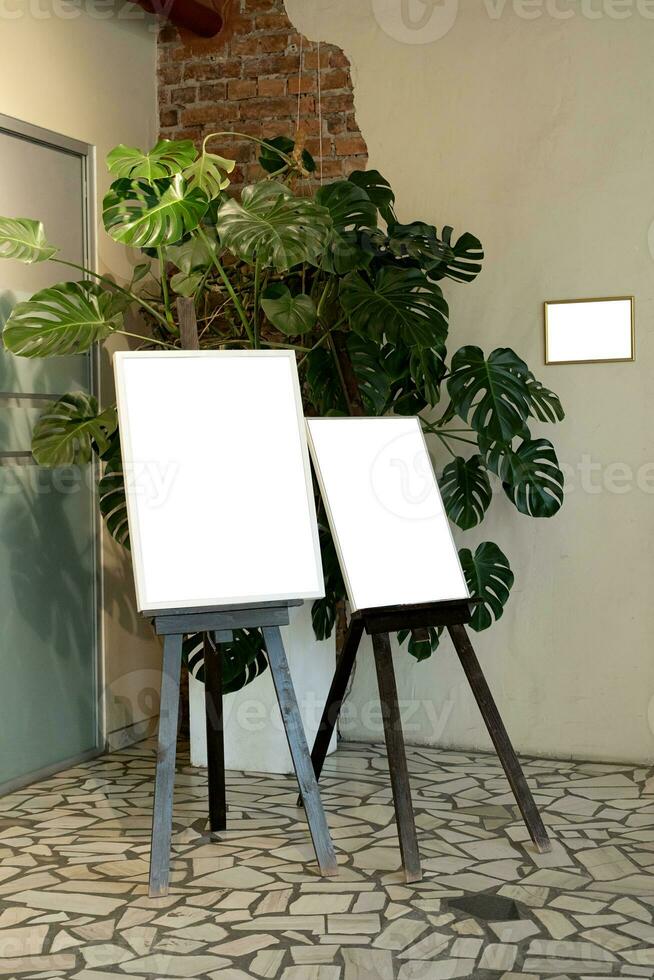 Blank picture frames on brick wall with glowing lamp, mock up photo
