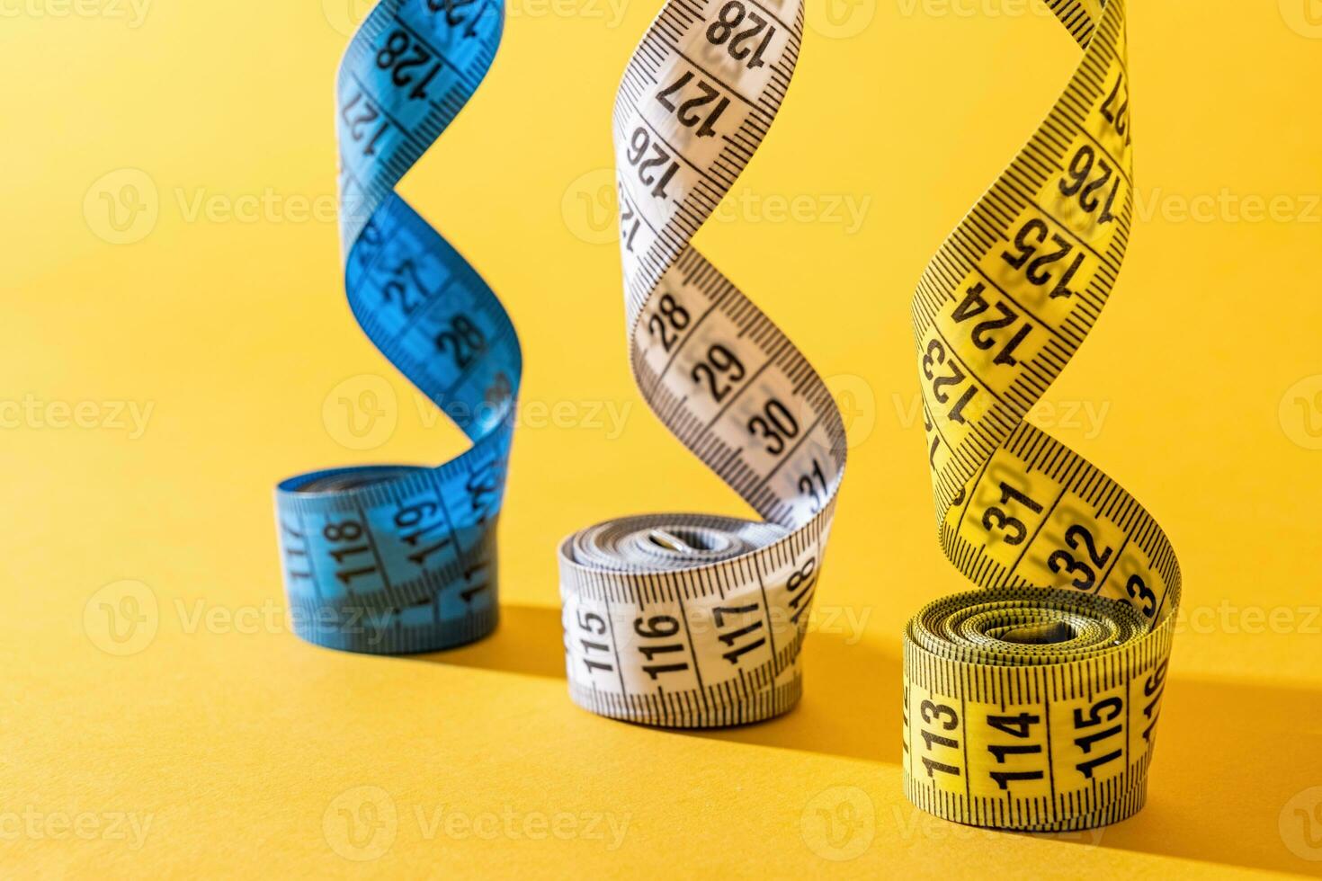 colorful measuring tapes top view on bright yellow background photo
