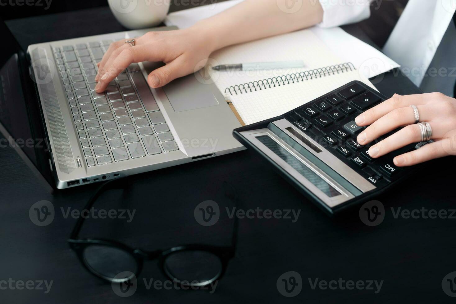 Efficient Accounting. Woman Uses Calculator and Laptop in Office, Embracing Finance and Accounting, Even When Working from Home photo