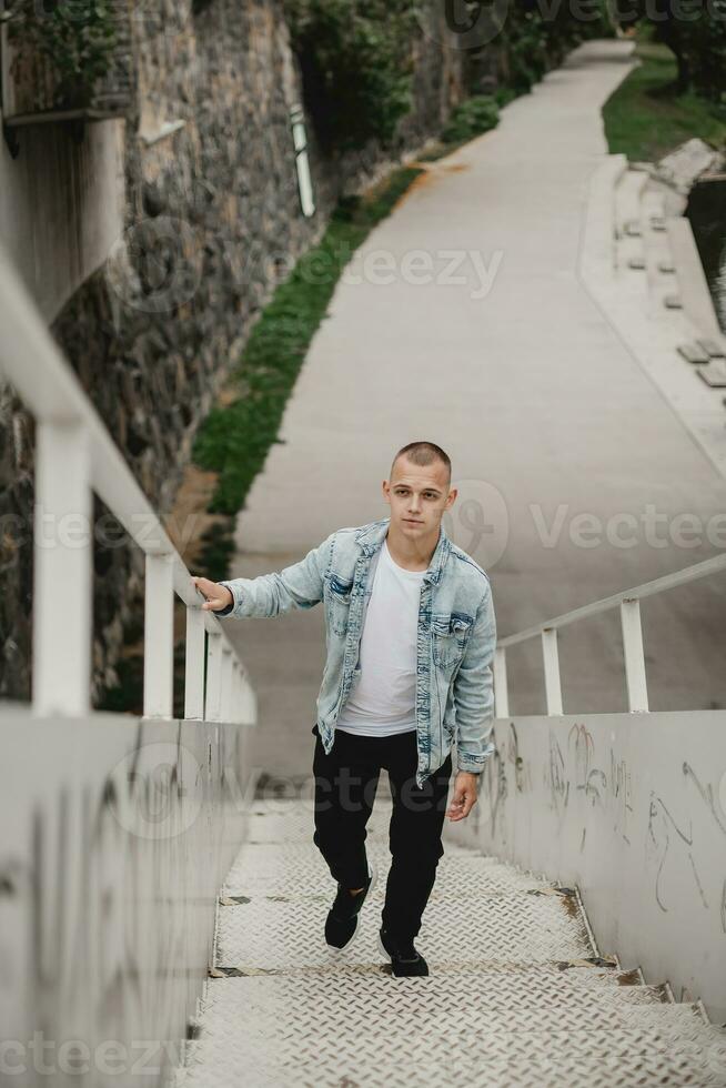 Trendy Caucasian Guy Ascending City Stairs in Urban Lifestyle. Young Man Climbing Stairs in the City. Modern Urban Exploration. Stylish Guy Climbing City Stairs. Handsome Guy Ascending Stairs photo