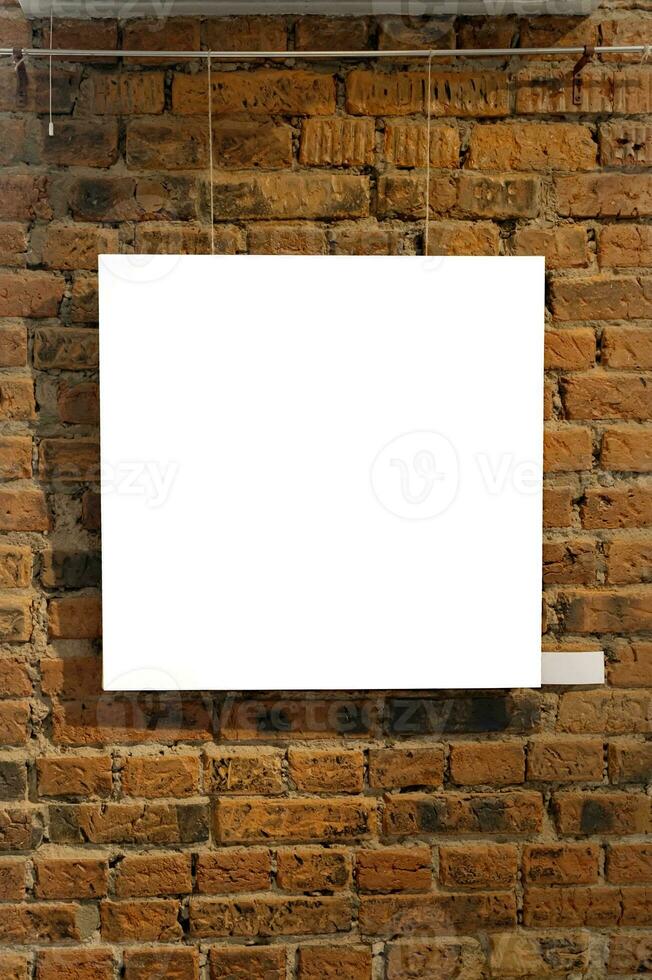 Blank picture frames on brick wall with glowing lamp, mock up photo
