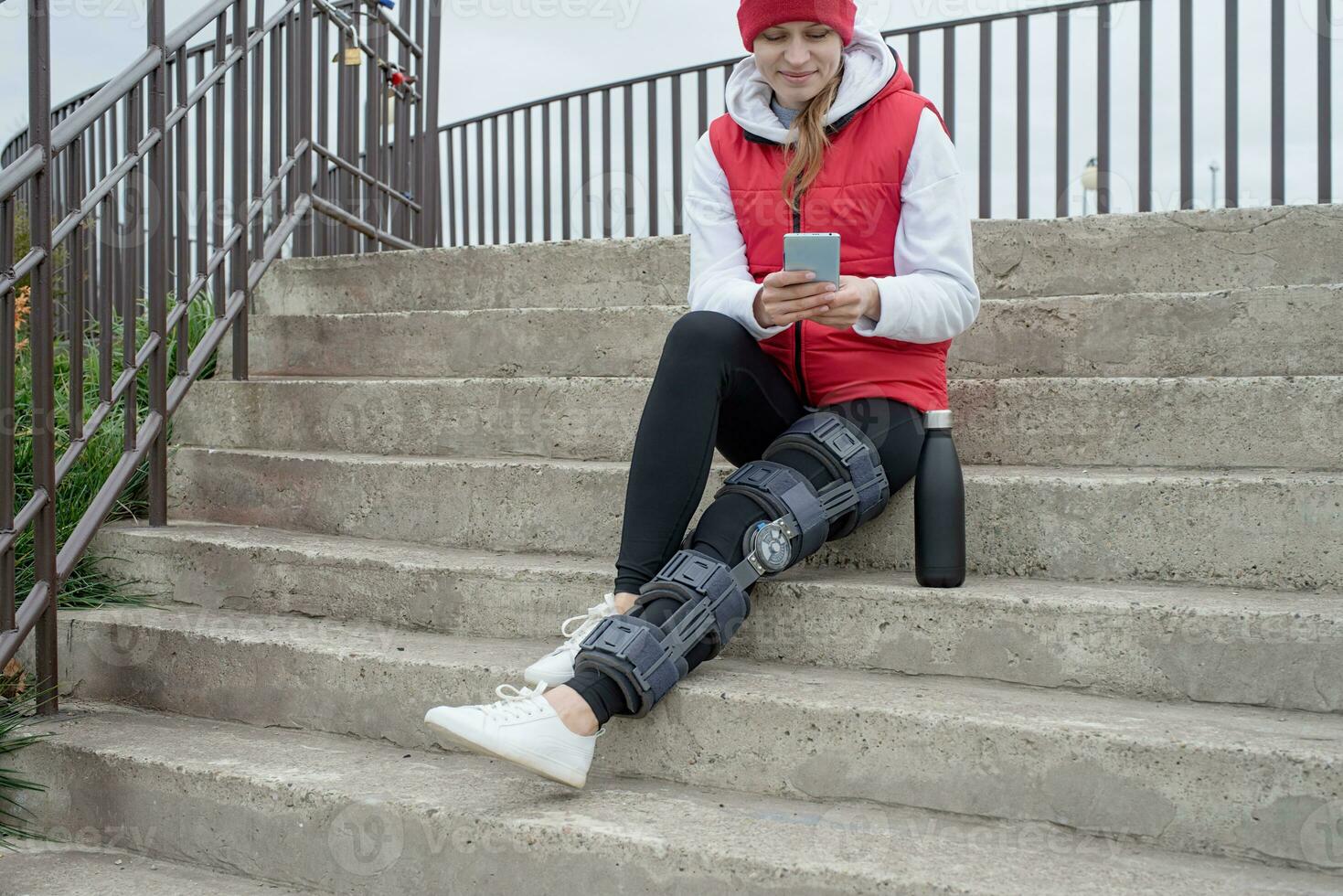 mujer con rodillera u ortesis después de una cirugía de pierna, caminando en el parque foto