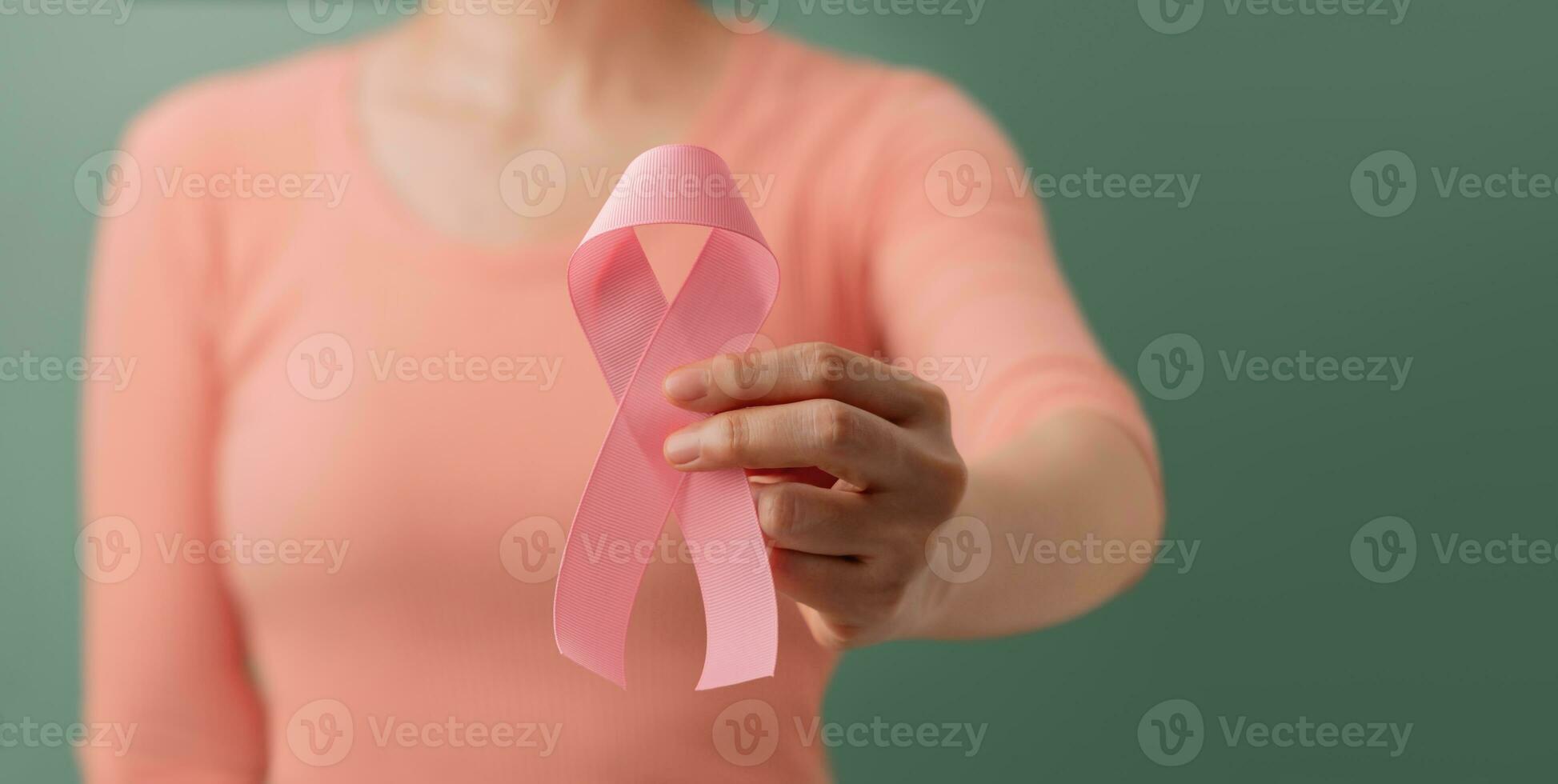 Breast Cancer Awareness Campaign Concept. Women Healthcare. Close up of a Young Female Brings a Pink Ribbon into the Front. photo