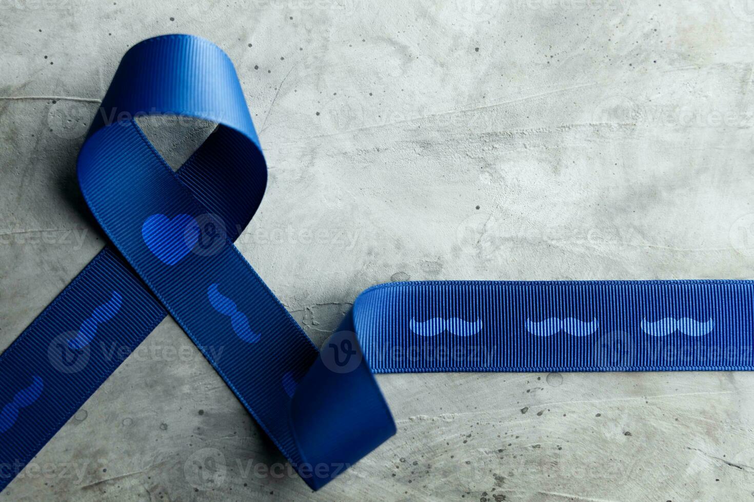 Prostate Cancer Awareness Campaign Concept. Men Healthcare. Close up of a Blue Moustache Ribbon  Lying on Rough Grey Cement Concrete background, Top View photo