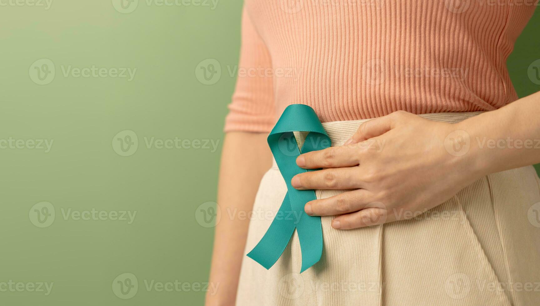 Ovarian and Cervical Cancer Awareness. Woman Holding Teal Ribbon on Lower Abdomen, Uterus, Female Reproductive System, Women's Health, PCOS and Gynecology photo