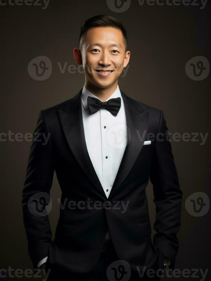Smiling young man of Asian descent dressed in suit on gray background AI Generative photo