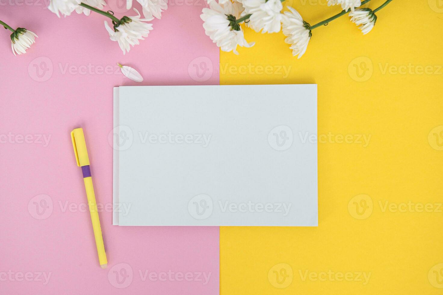 A clean notebook and pen on a light pink and yellow table. Mockup with a bouquet of flowers photo