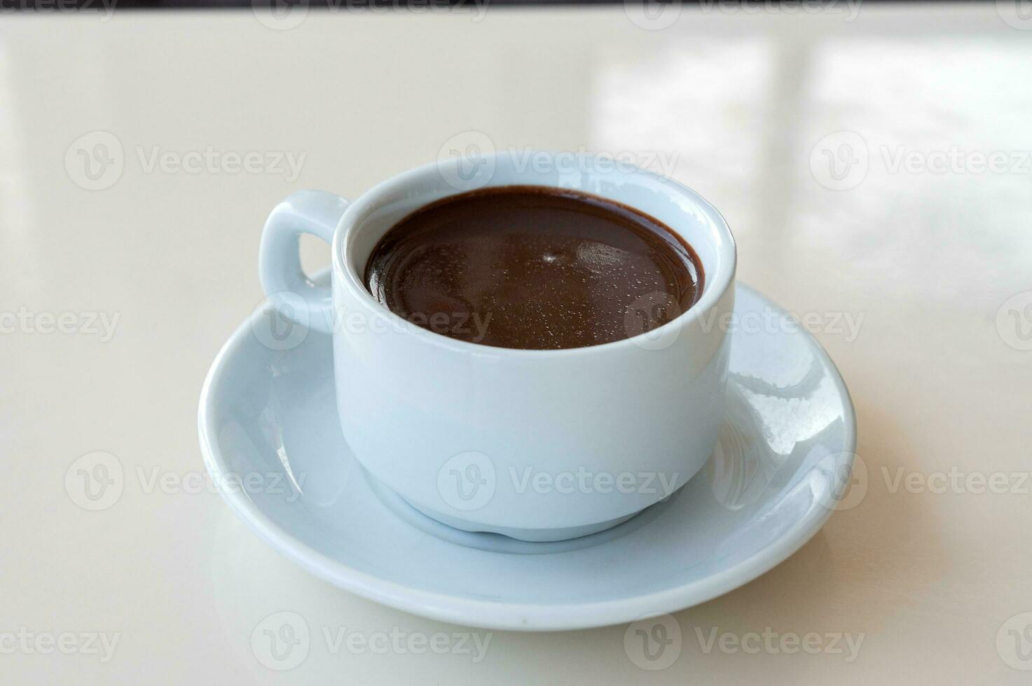 Hot bitter chocolate in a white mug is on the table photo