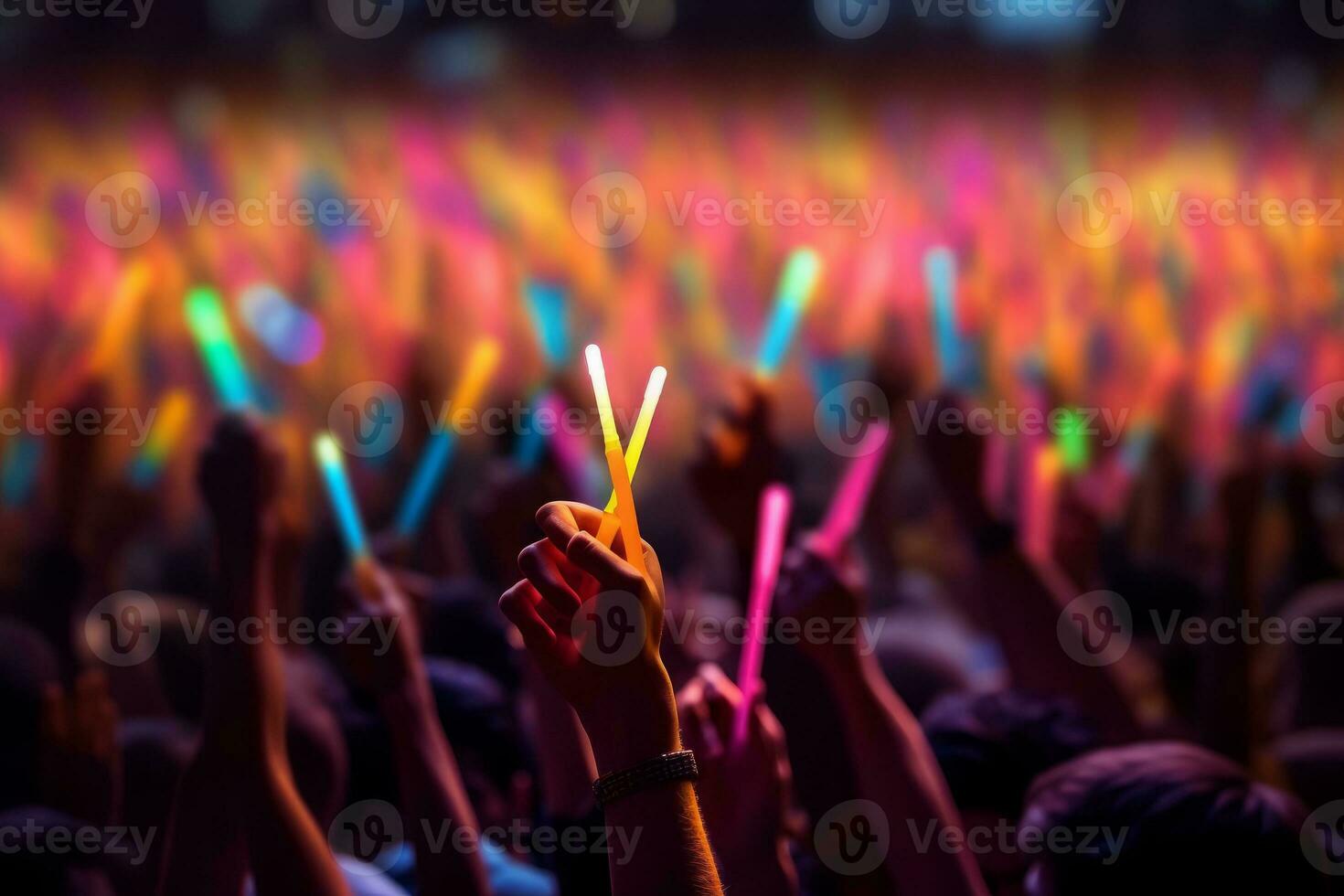 A close-up shot of hands holding glow sticks in the air at a rave party with a blurry crowd of people dancing in the background. Generative Ai photo