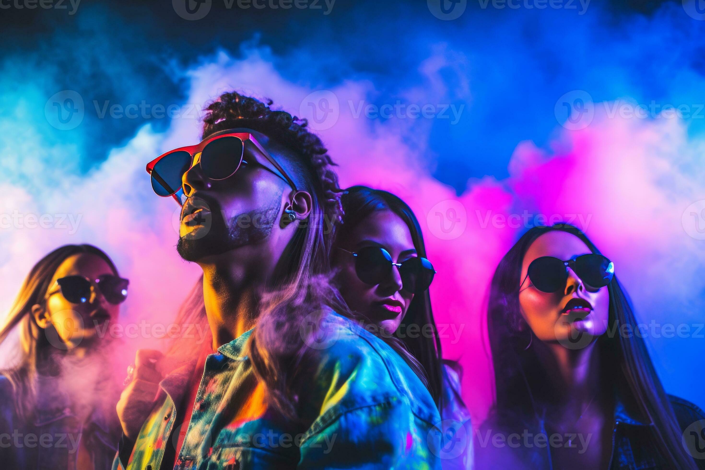 Group of young people wearing neon clothes and sunglasses dancing at a rave  party in front of a DJ booth with colorful lights and smoke effects in the  background. 31549312 Stock Photo