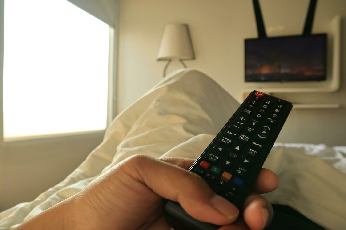 Man with remote control in hand watching random channel and pressing button on remote control. Remote control in hand closeup photo