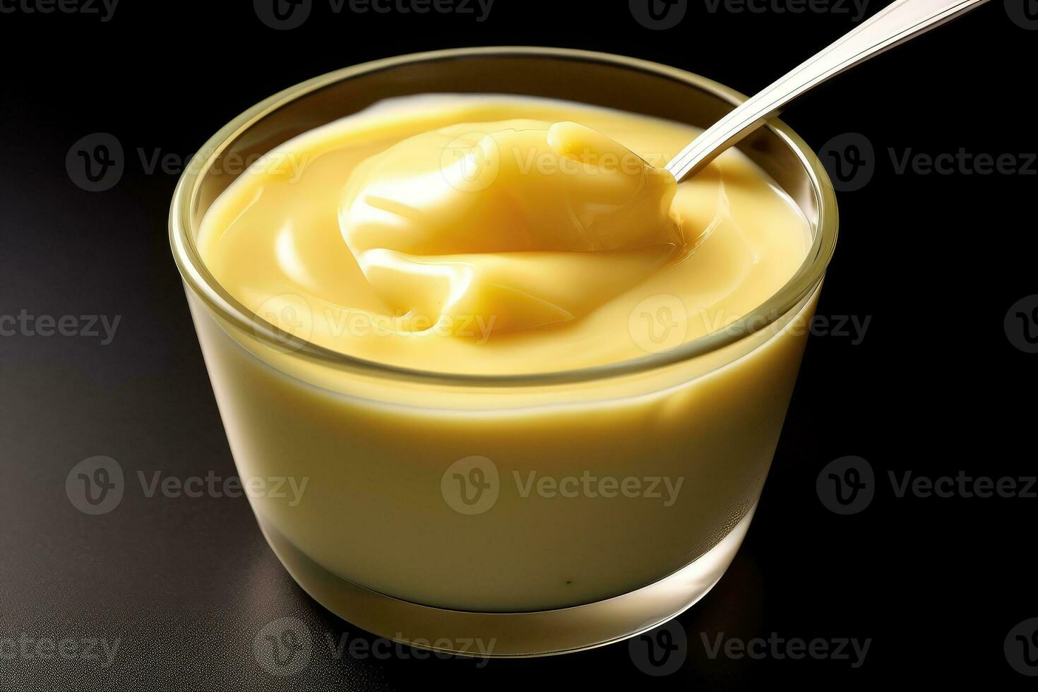a spoon is in a glass of yellow custard photo