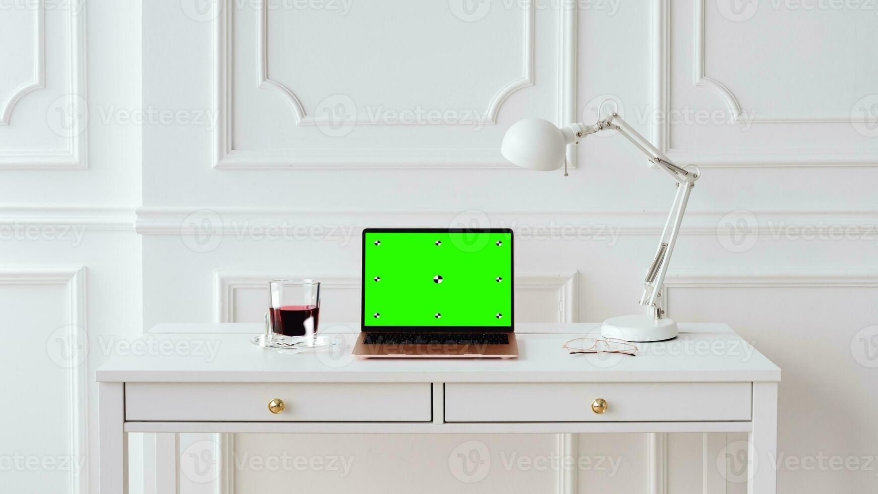 Workplace with laptop computer on desk with blank empty green mockup screen for advertising standing in modern contemporary office. Business software website ads technology concept. photo