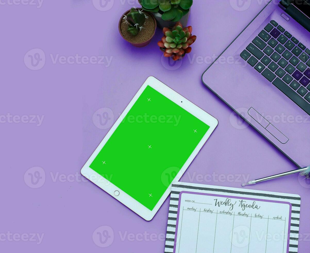 Top view of a streamlined work-from-home workspace with essential gadgets and a green screen setup. This minimalist arrangement is perfect for efficient remote work, virtual meetings, creatives. photo