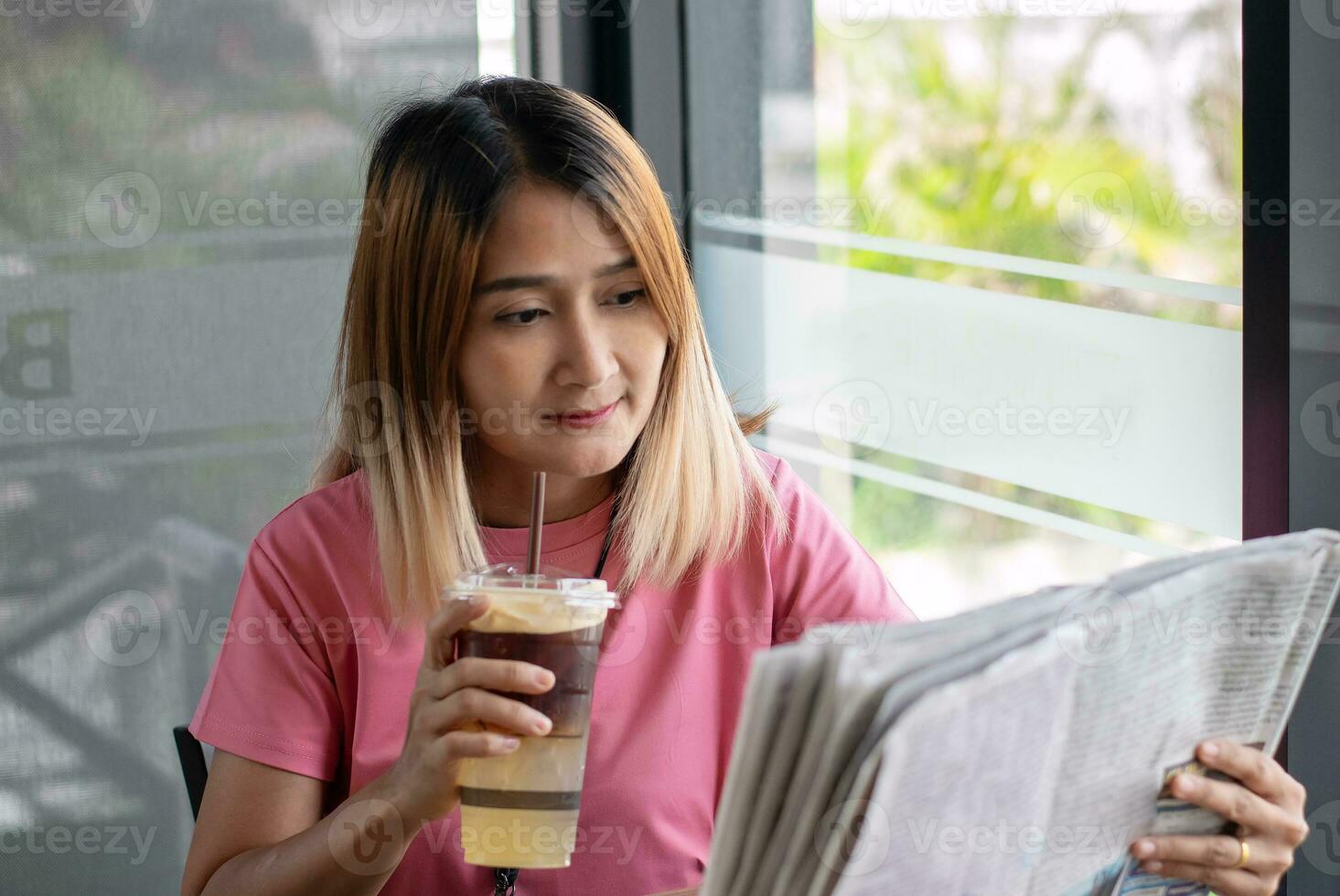 Mature adult woman sitting at cafe  holding lemonade juice  and reading newpaper daily information for learning planning lifestyles,lesiure activity vacation. photo