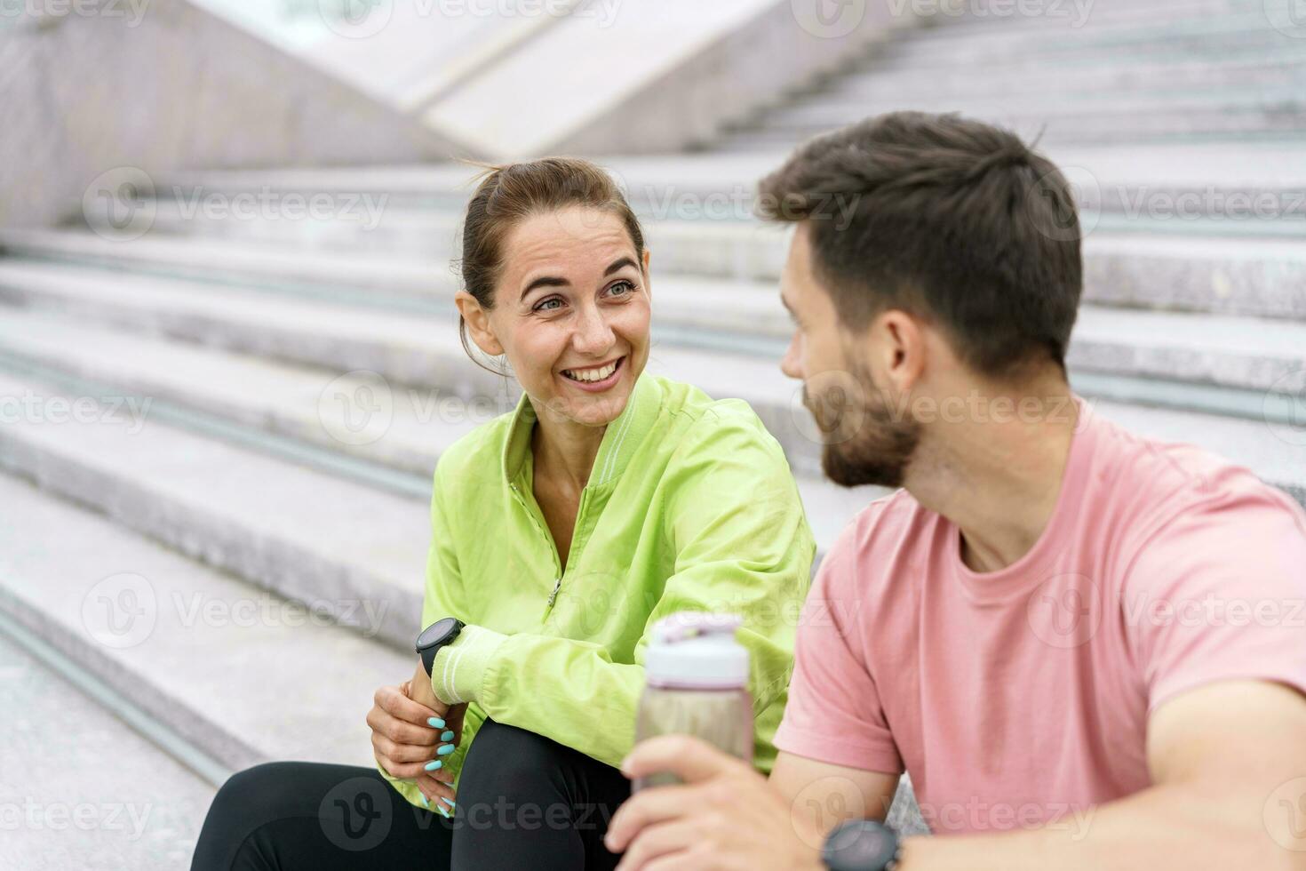 Break coach and client workout fitness outdoors. A woman and a man are friends in fitness clothes for sports. People use fitness watches and running shoes. photo