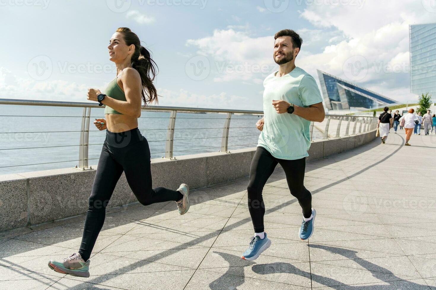 People in sportswear together runners, physical education and sports. Running man and woman train.  Using smart watches and a fitness app.  Team exercises of a young couple. photo
