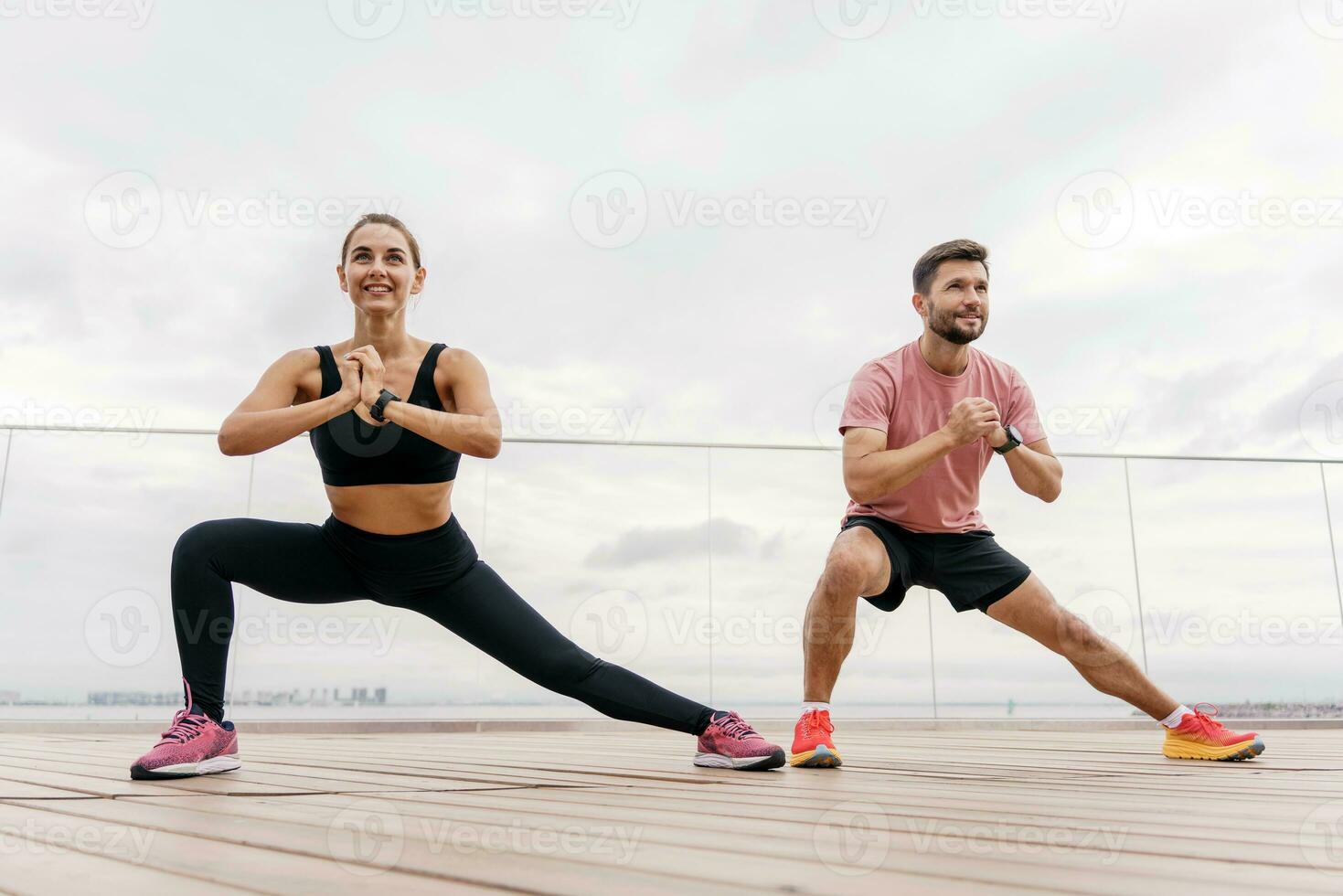 The trainer and the client teach fitness exercises. People in sportswear and sneakers are doing sports. A person uses a fitness watch. A man and a woman train together. photo