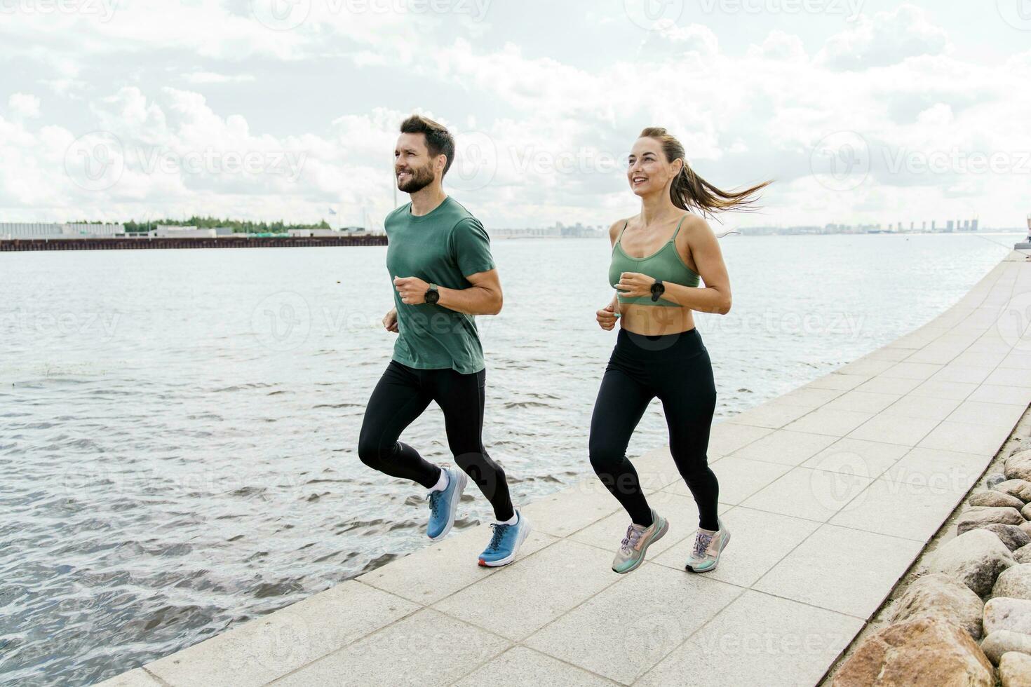 People in sportswear together runners, physical education and sports. Running man and woman train.  Using smart watches and a fitness app.  Team exercises of a young couple. photo