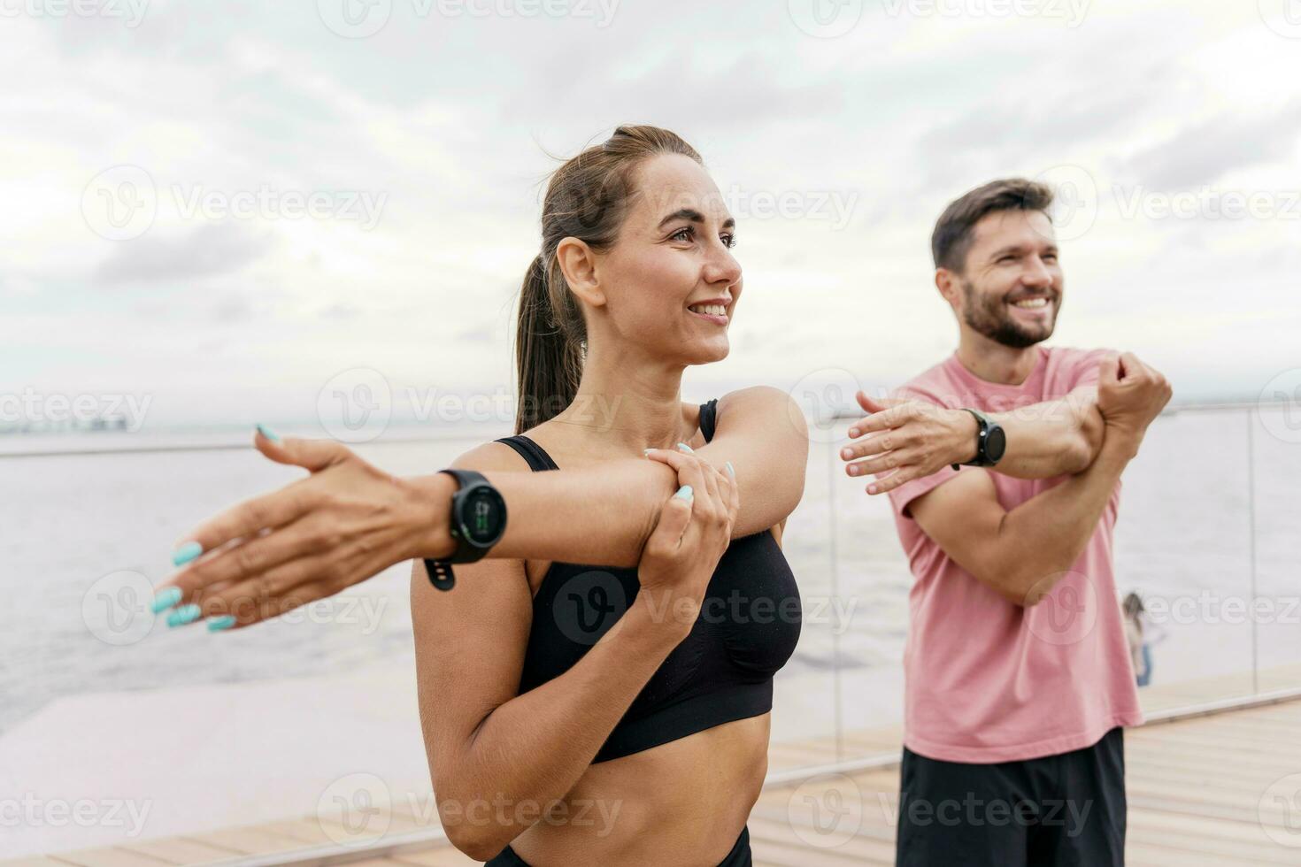 Athletes train together. A woman and a man are getting ready for a run. Fitness friends do exercises for a healthy lifestyle. Use a fitness watch and wristband to work with the app. photo