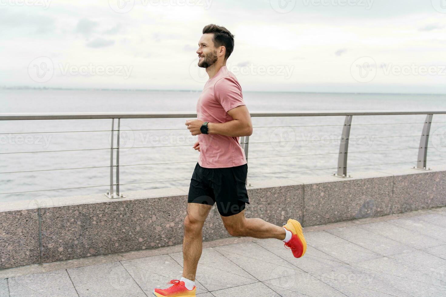 The running coach is a man and trains outdoors. Runner athlete in fitness clothes and running shoes, full-length. Uses a fitness watch for a strong person and sports for health. photo