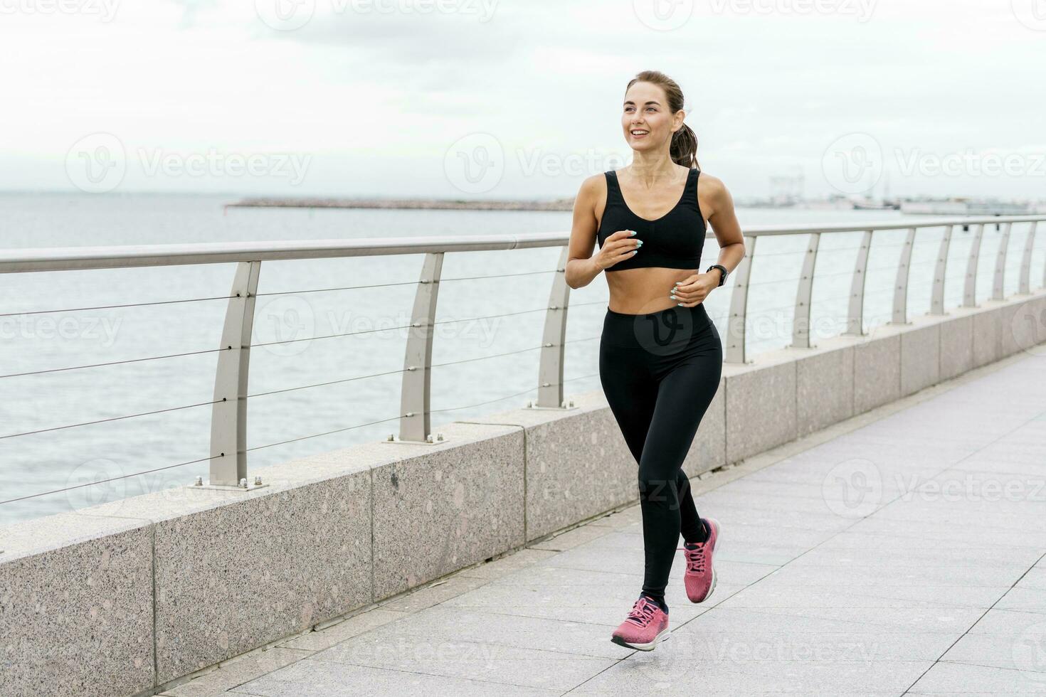 A woman running coach smiles and trains in the fresh air. Runner athlete in fitness clothes and running shoes. A strong person and sports for health. photo