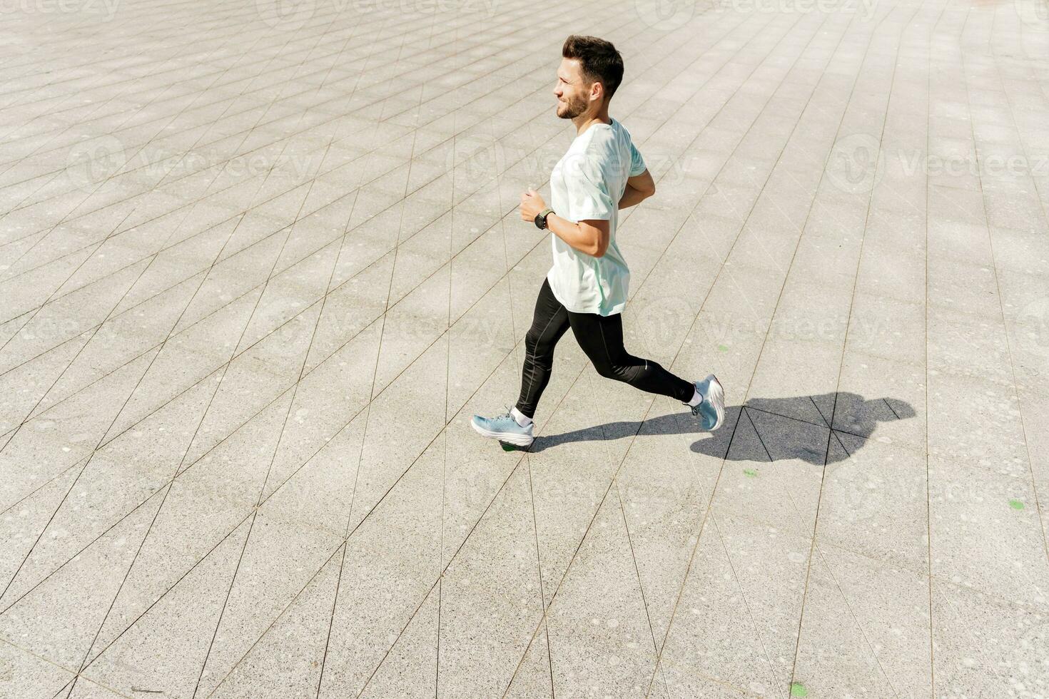 A man training fitness in a comfortable T-shirt. A coach with glasses does a running exercise every day, a healthy lifestyle. A sporty person Uses a fitness watch and a running app. photo