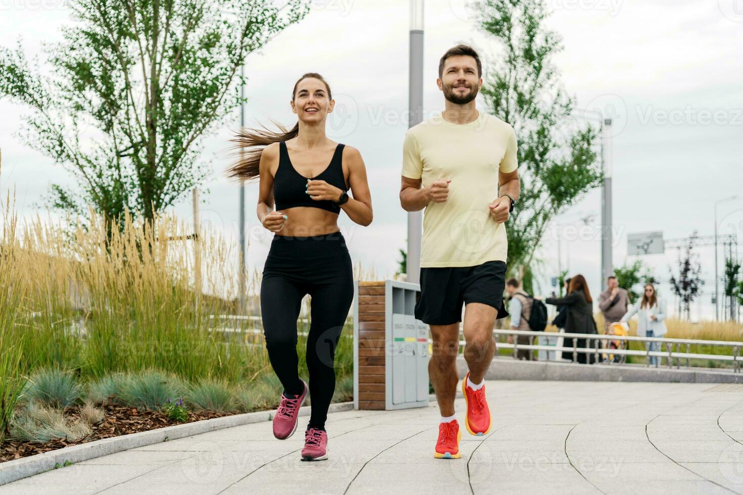 Male and female athletes training fitness and running. People in sportswear together, physical education and sports. Young couple exercises in full height. Enjoy the fitness watch and the app. photo