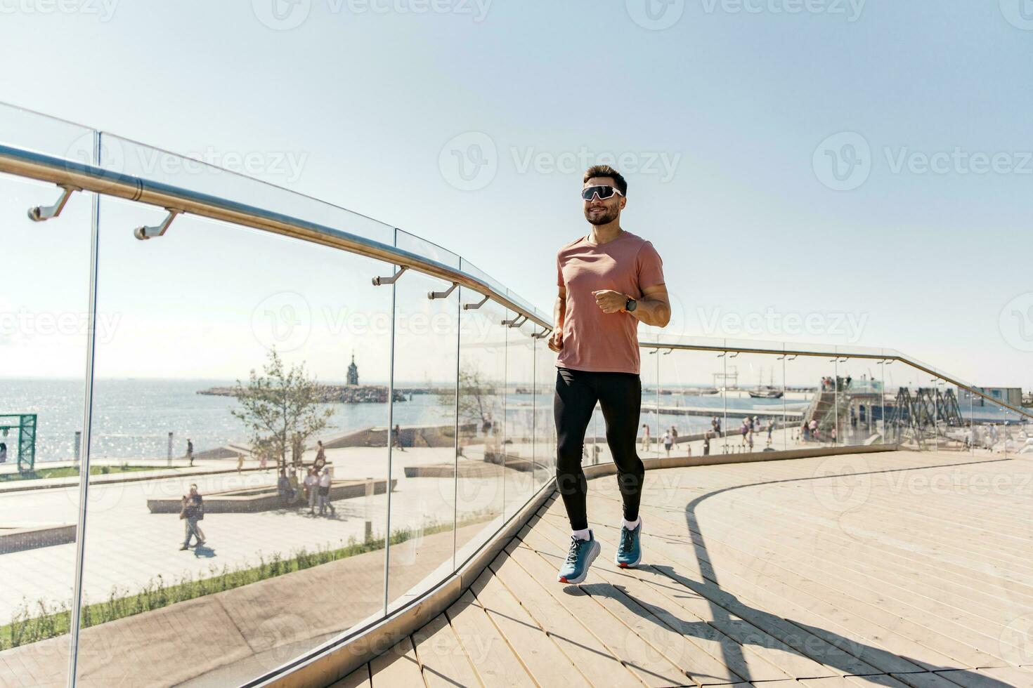 Athlete runner full-length workout in sportswear. Uses a fitness watch and an app. A sporty man running a lot. Man running in the city fresh air. photo