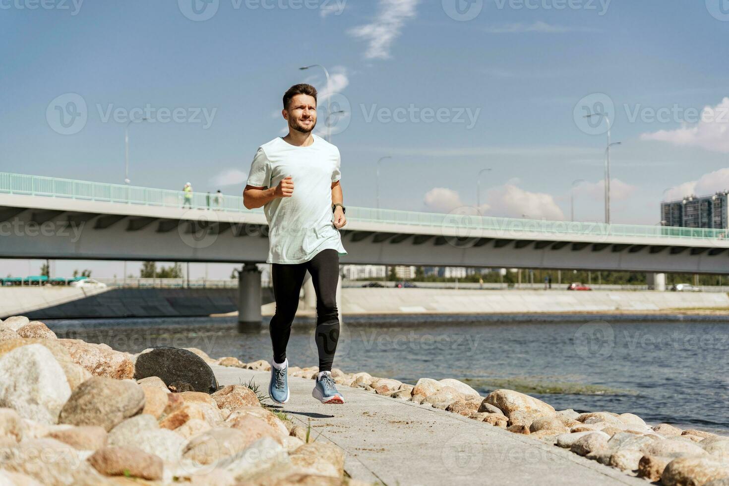 A man training fitness in a comfortable T-shirt. A coach with glasses does a running exercise every day, a healthy lifestyle. A sporty person Uses a fitness watch and a running app. photo