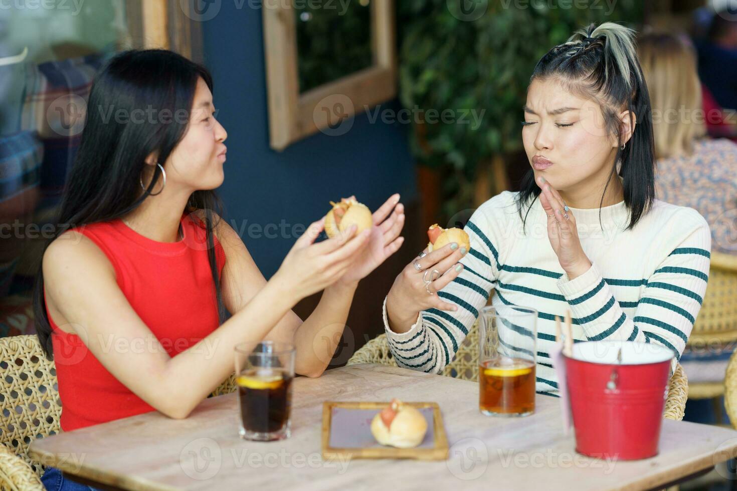 Satisfied Asian women eating tasty meal in cafe together photo