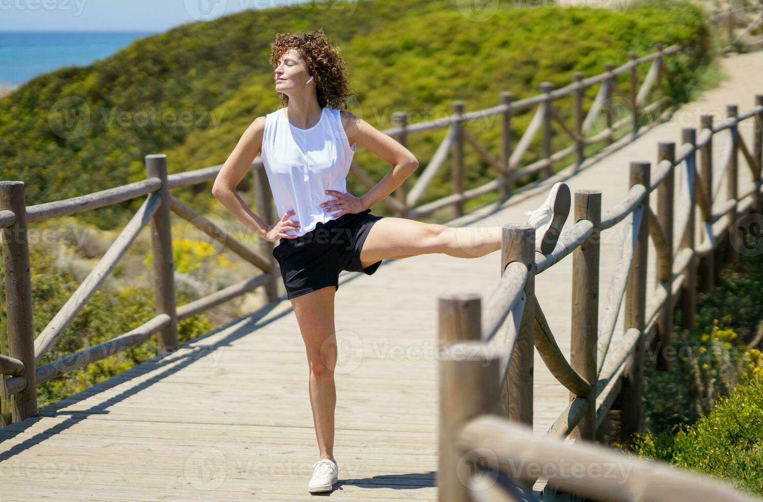 Happy young woman warming up with stretching leg on bridge photo