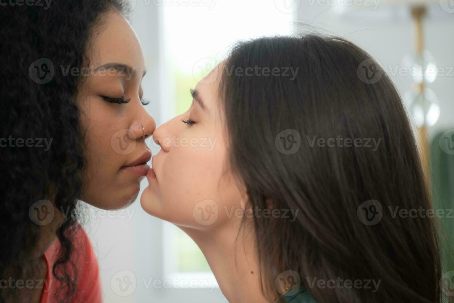 Young African American woman kissing her friend on the lips. photo