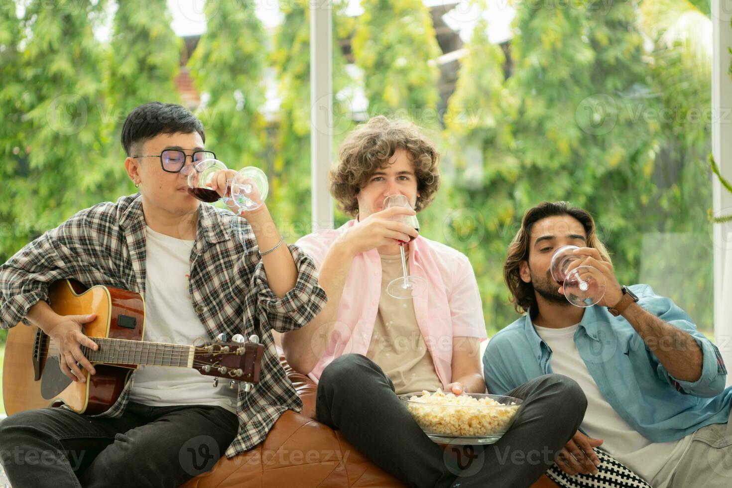 Multiethnic group of friends having fun playing guitar and singing together at home photo