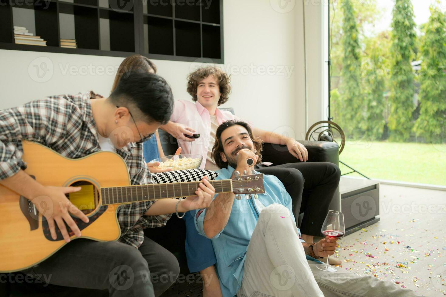 Multiethnic group of friends having fun playing guitar and singing together at home photo