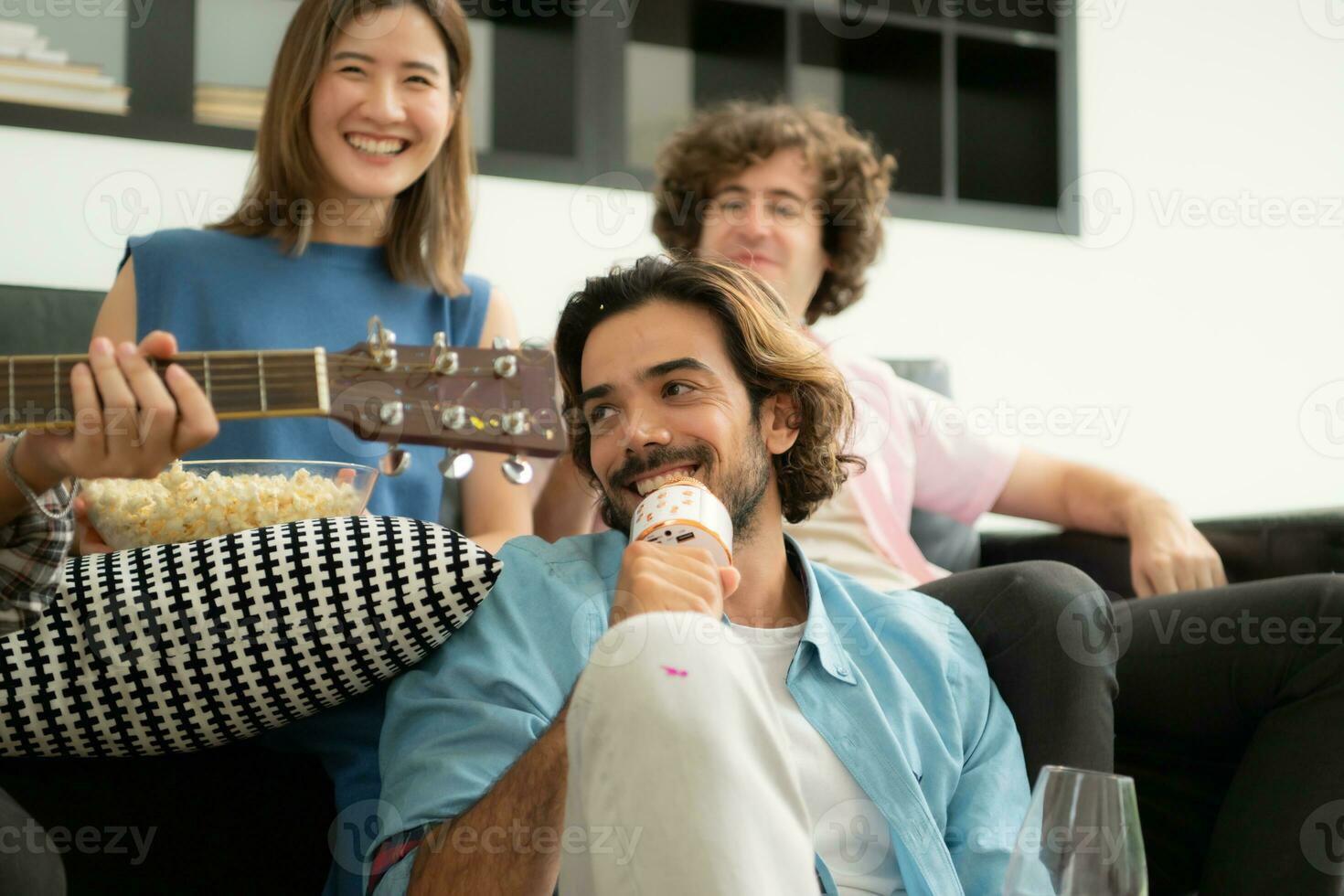 Multiethnic group of friends having fun playing guitar and singing together at home photo