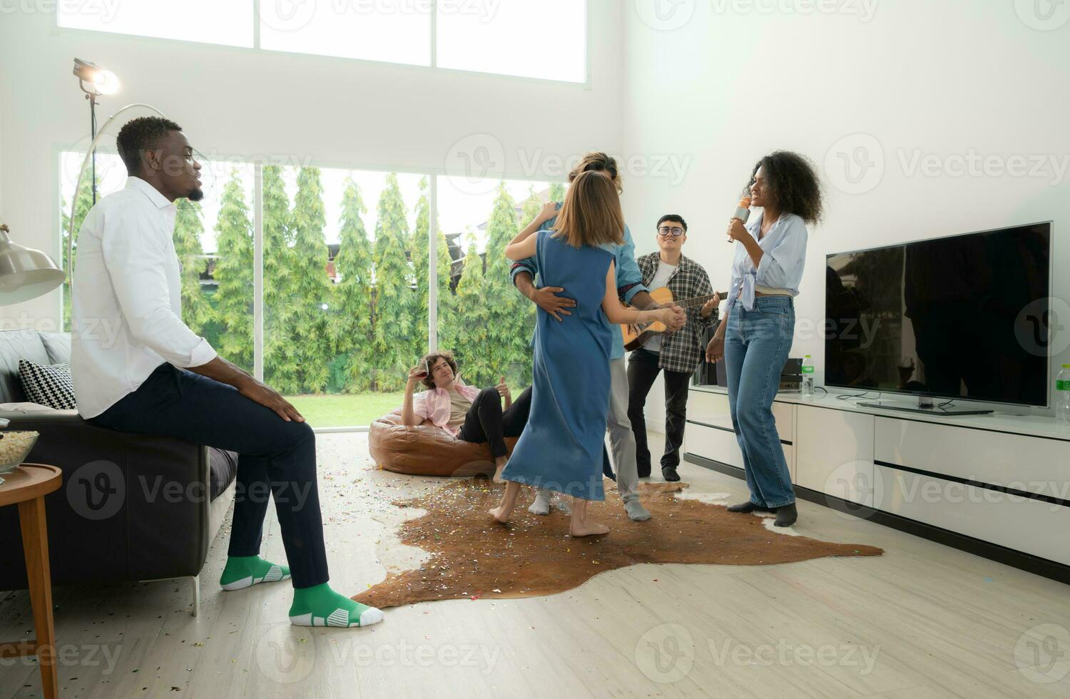 Group of multiethnic friends having fun at party by playing guitar and singing together at home. photo