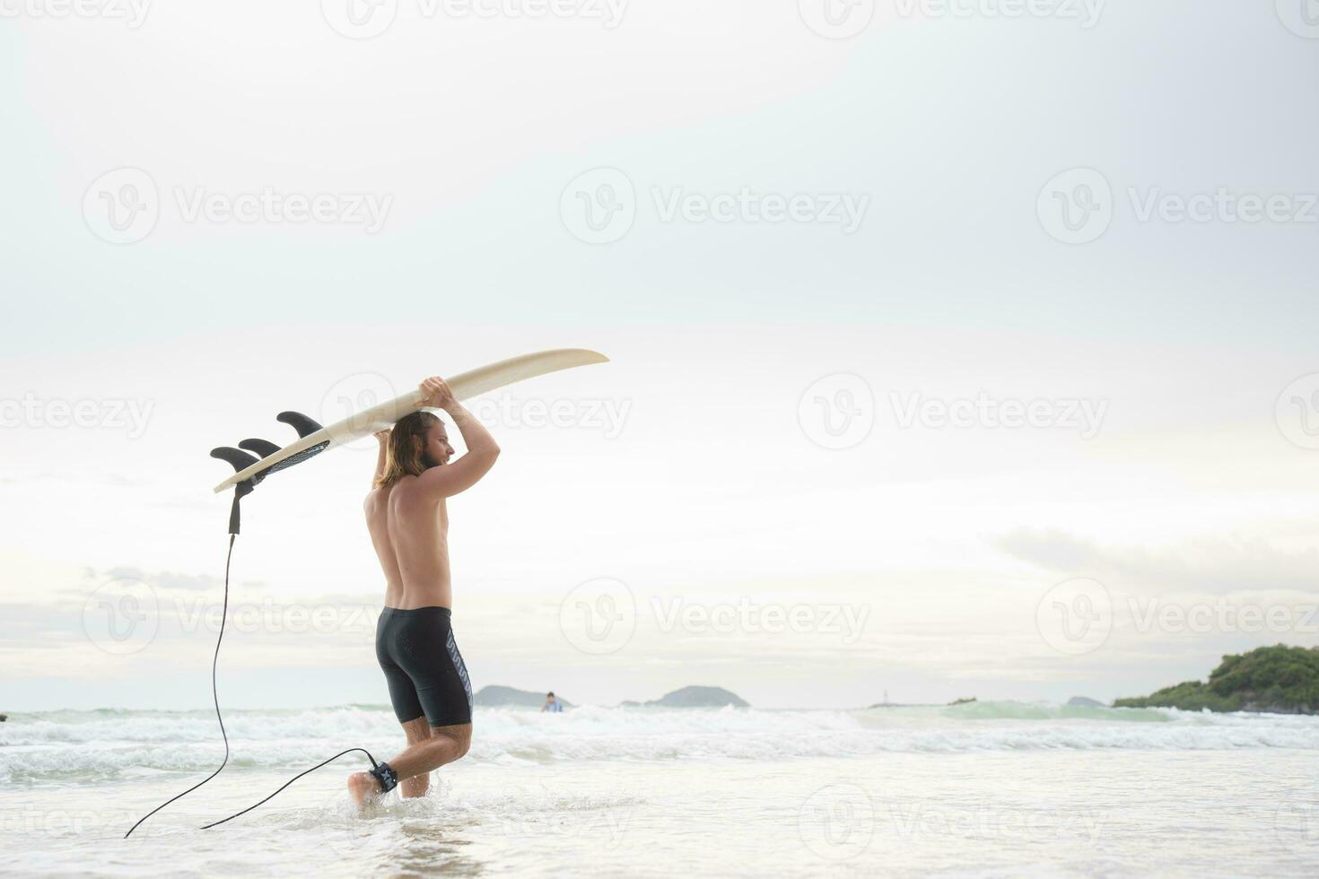 Surfer man with his surfboard on the beach. photo