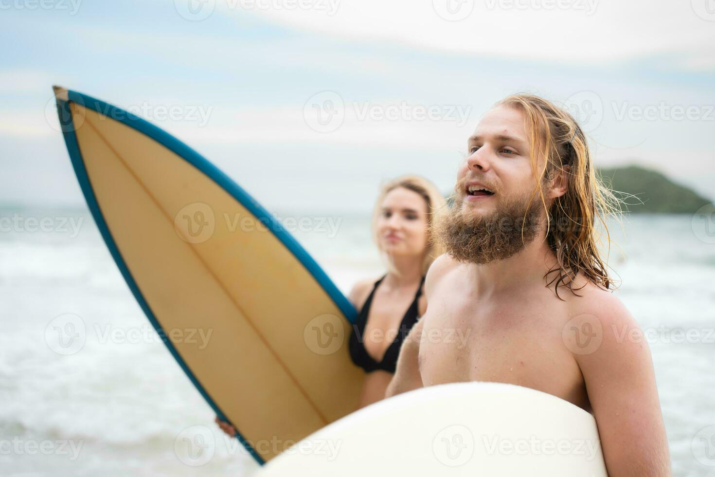 Couple of surfers holding hands and looking at each other on beach photo