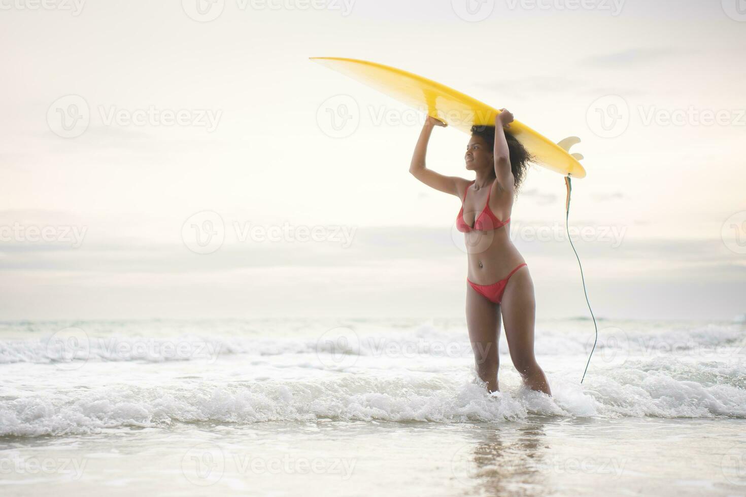 Surfer girl with her surfboard on the beach. photo