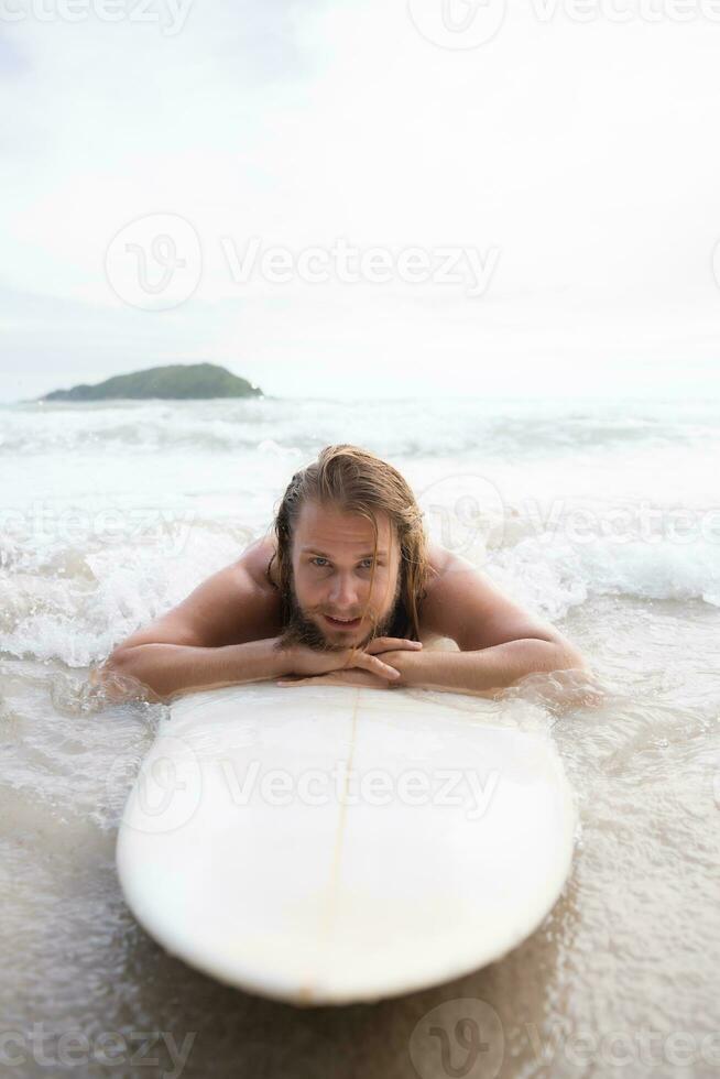 Surfer man with his surfboard on the beach. photo