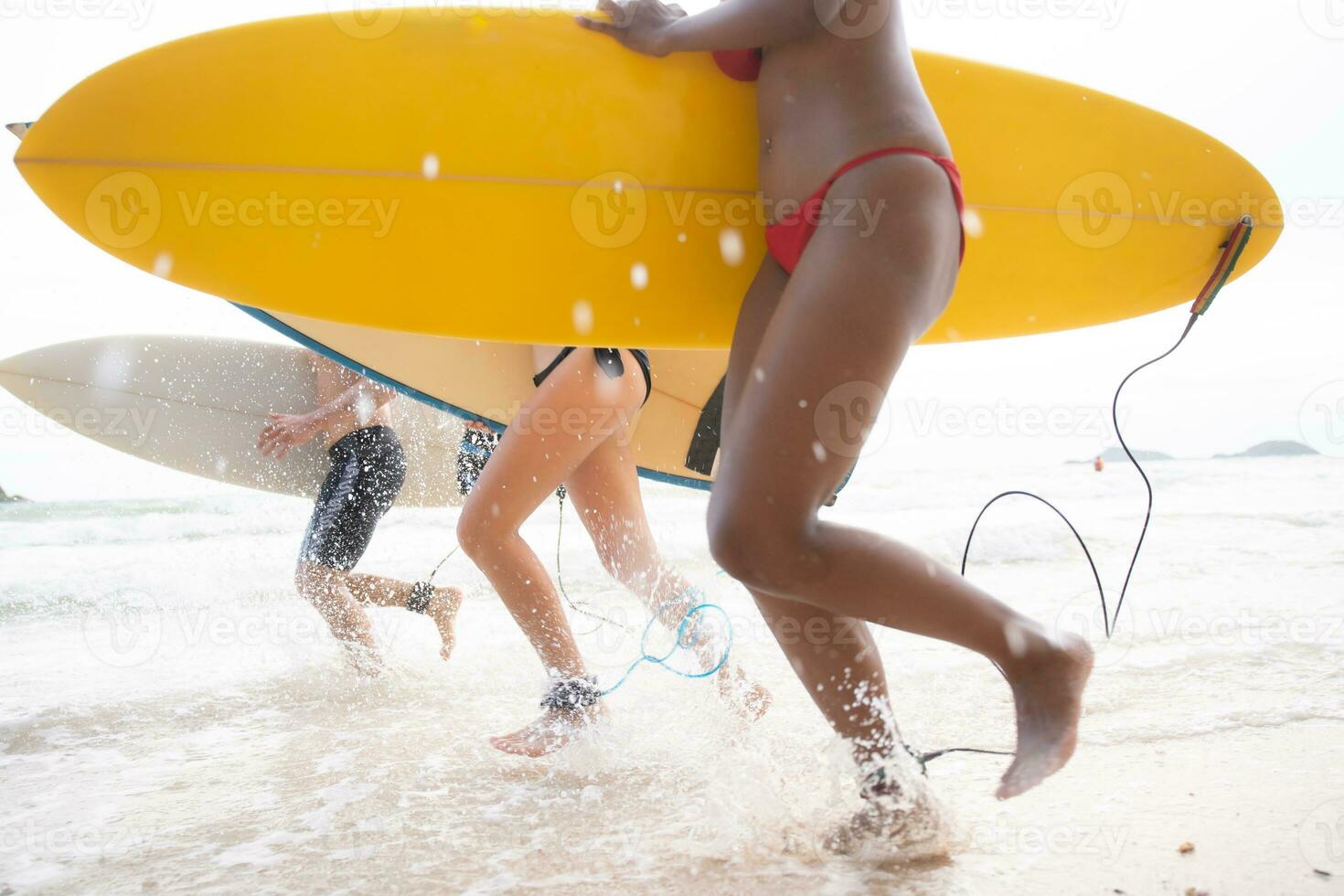 Two women and young man holding surfboards ready to walk into the sea to surf. photo