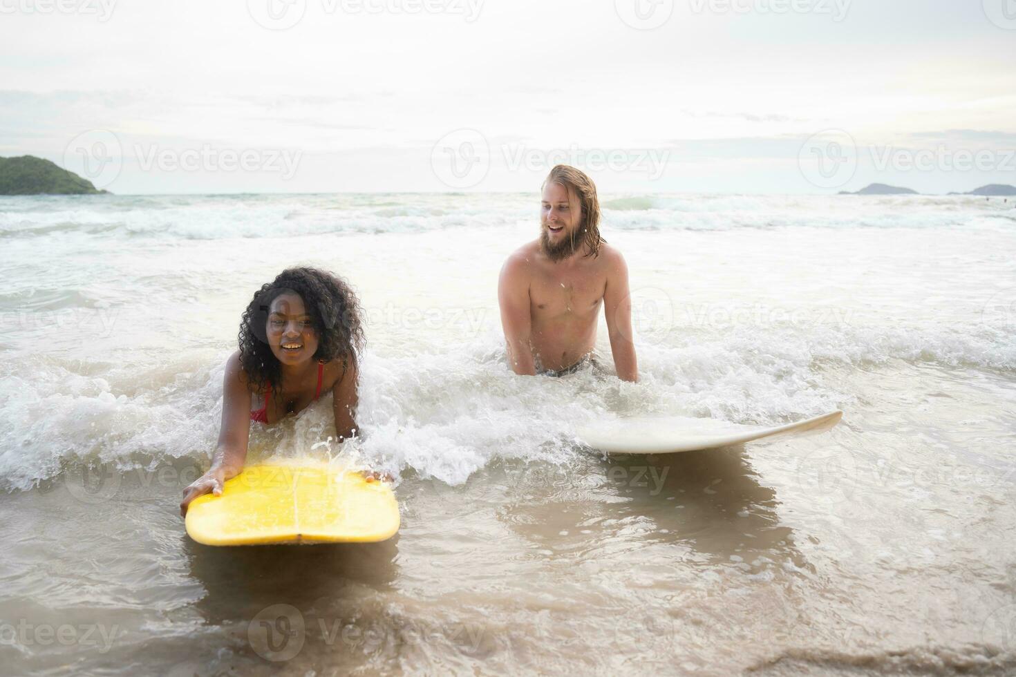 Young man and woman having fun with surfboard in the ocean on a sunny day photo