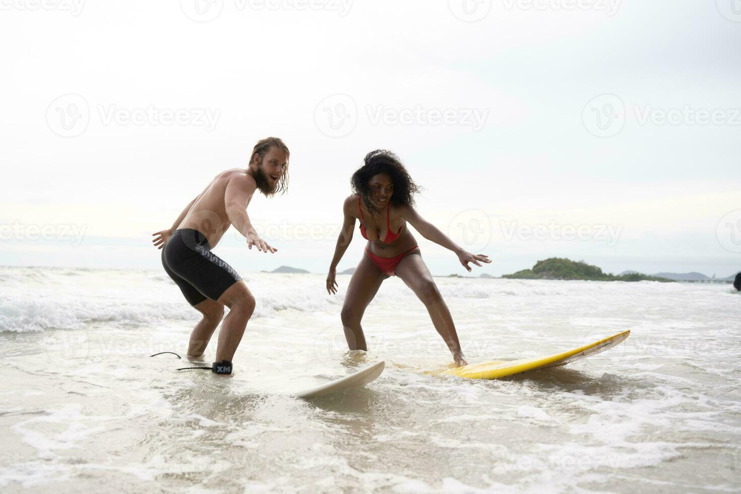 Couple surfing on the beach having fun and balancing on the surfboard photo