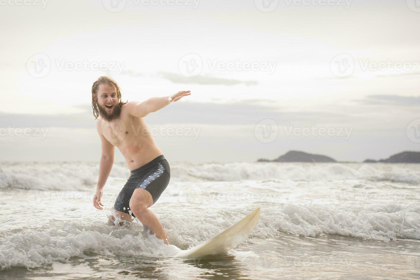 Young man surfing on the beach having fun and balancing on the surfboard photo