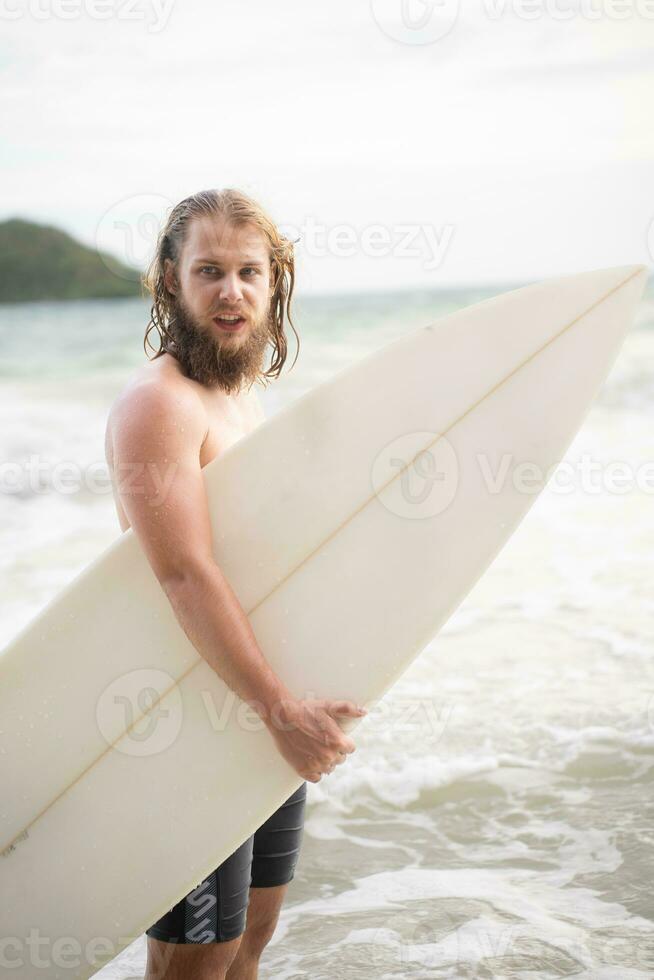 Surfer man with his surfboard on the beach. photo